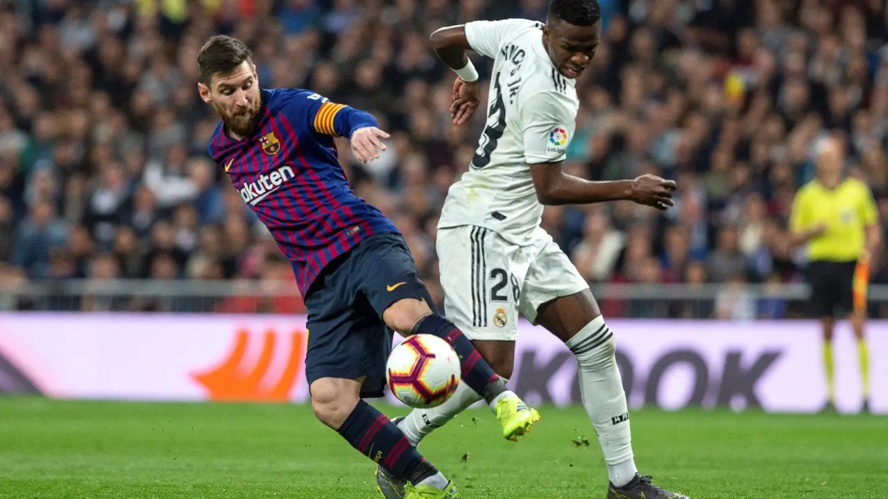 Fotograf&iacute;a de archivo, tomada en marzo de 2019, en la que se registr&oacute; al argentino Lionel Messi (i), al actuar para el FC Barcelona, al diputar un bal&oacute;n con el brasile&ntilde;o Vinicius Jr, delantero estrella del Real Madrid, durante un Cl&aacute;sico del f&uacute;tbol en Espa&ntilde;a, en el estadio Santiago Bernab&eacute;u de Madrid. EFE/Rodrigo Jim&eacute;nez